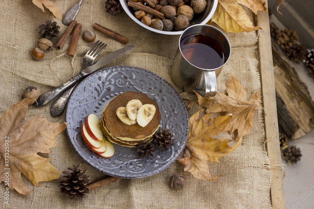 Fototapeta premium A composition of nuts, pancakes, bananas and apple on a nice autumn themed background