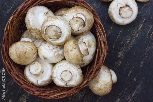 fresh mushrooms in a basket on the wooden table.