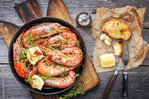 Traditional fried black tiger prawn with garlic bread as top view in a black frying pan photo
