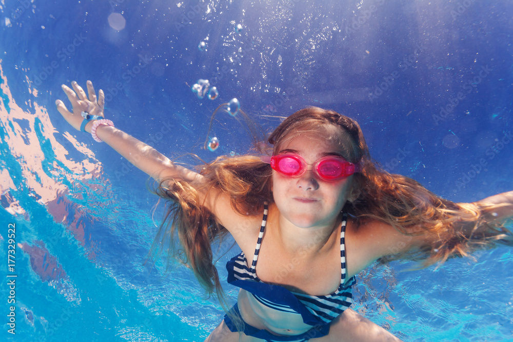 Girl in goggles learning holding breath underwater