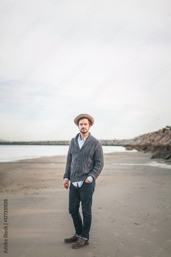 Portrait of stylish man wearing a hat and cardigan on the beach. Portrait of stylish man wearing a hat and cardigan on the beach.