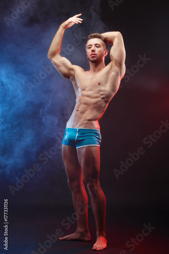 Power, strength, excellent body, bodybuilding, sports concept. Studio shoot of young handsome muscular fit handsome shirtless man with perfect six-pack abs and hands, vertical image
