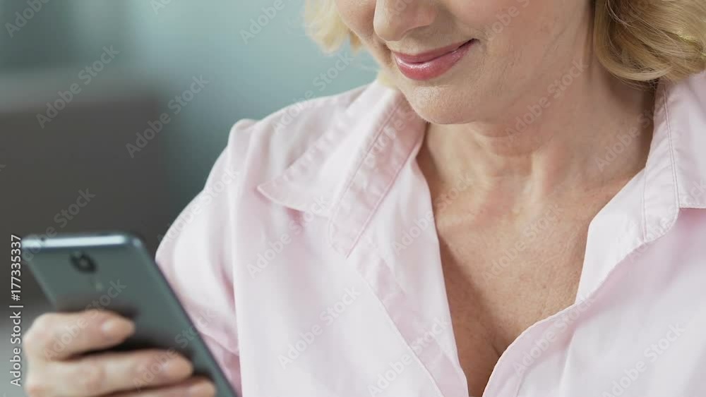 Pretty middle-aged female viewing children's photos on smartphone, close-up Pretty middle-aged female viewing children's photos on smartphone, close-up