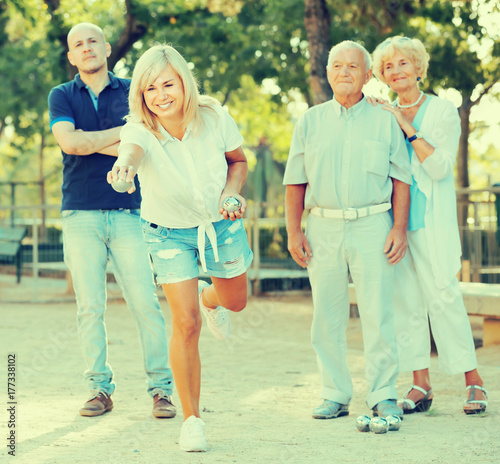 Happy mature woman with friends playing petanque