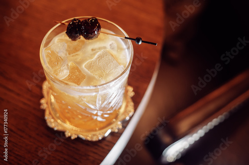 rich yellow cocktail with ice and cherry on a stick photo