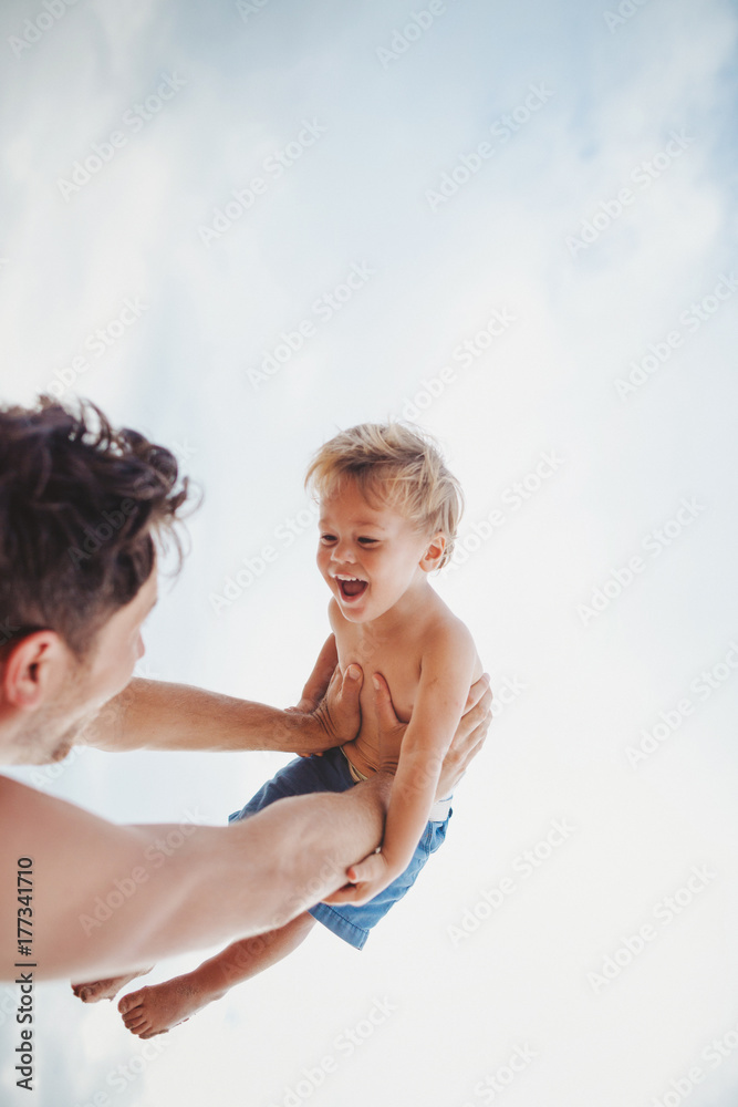 Young dad having fun with toddler son on tropical beach - lifting up high Young dad having fun with toddler son on tropical beach - lifting up high