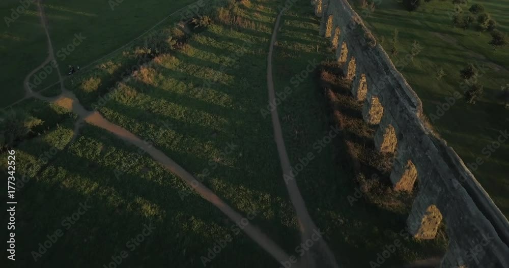 Video from above. Aerial view of the ancient Roman Aqueduct at sunset. Old ruins surrounded by a green public Park (Parco degli Acquedotti) Rome, Italy.