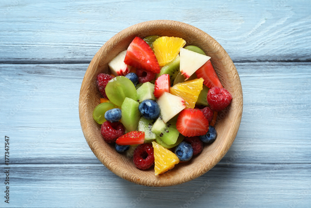Bowl with delicious fruit salad on wooden background Bowl with delicious fruit salad on wooden background