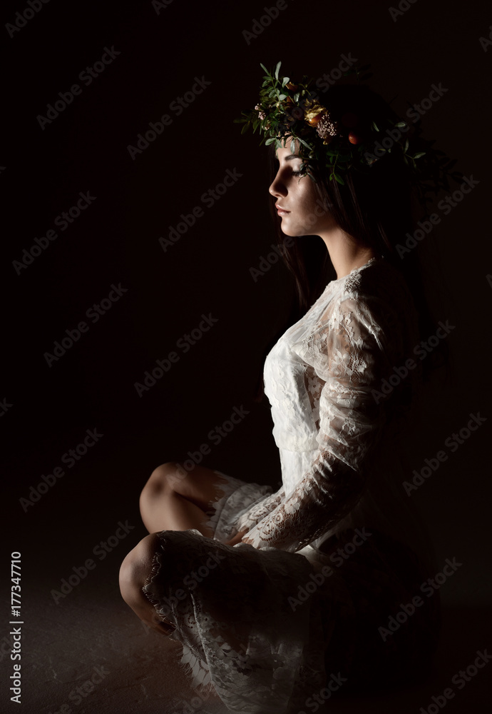Φωτογραφία Beautiful portrait of young woman with wreath of flowers sitting on a floor