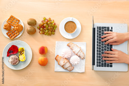 Hands of food blogger with laptop and different products on table
