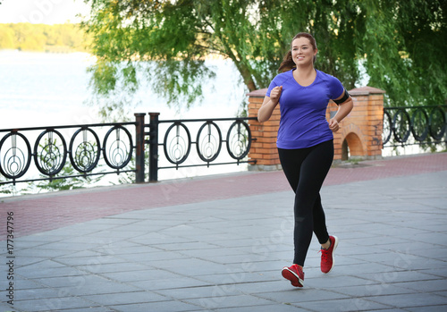 Overweight young woman jogging in park. Weight loss concept
