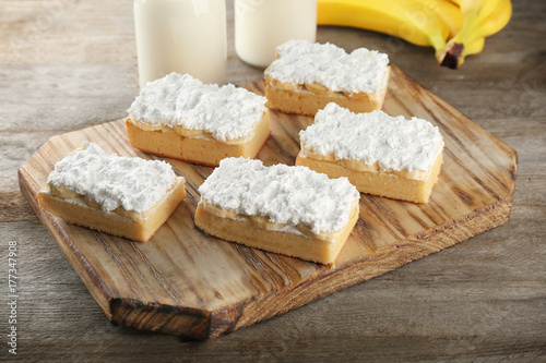 Wooden board with pieces of tasty banana cake on table
