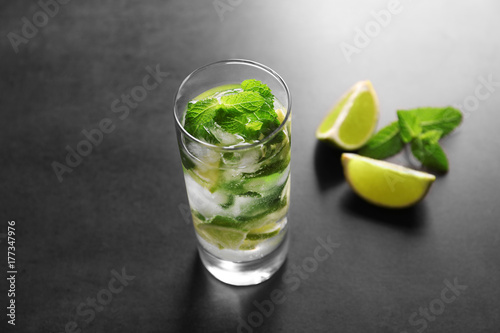 Glass of cocktail with lime and mint on grey background