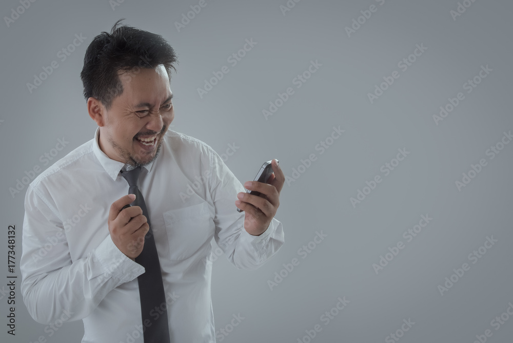 Portrait of businessman happy and holding smartphone on gray background. business, people, success, gladness and cheerful concept Portrait of businessman happy and holding smartphone on gray background. business, people, success, gladness and cheerful concept