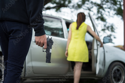 Bandit man with masked robber holding handgun weapon gangster to hijack hostage woman driver car shocked and dangerous on street violence concept