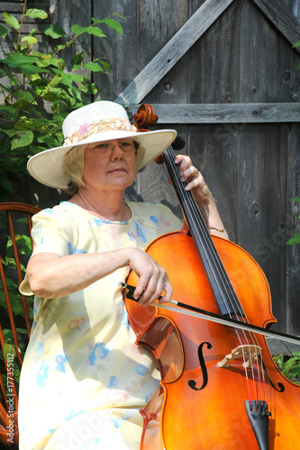Mature female cellist performing on her cello outdoors.