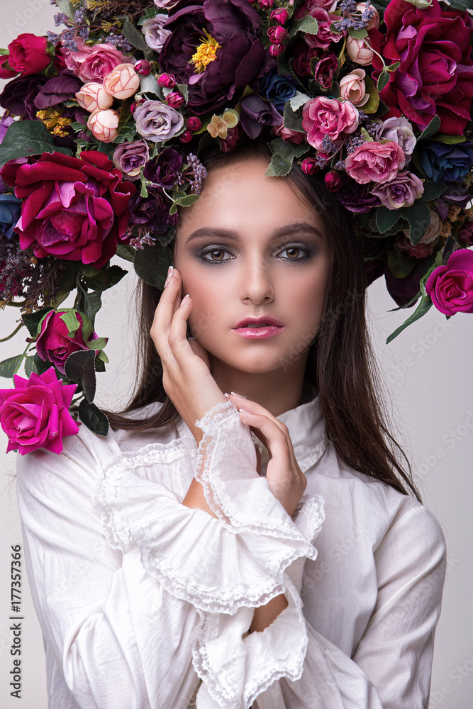 Naklejka premium Portrait of a girl model in a beautiful image with a wreath of flowers on her head in a photo studio. Fashion, style, beauty, portrait.