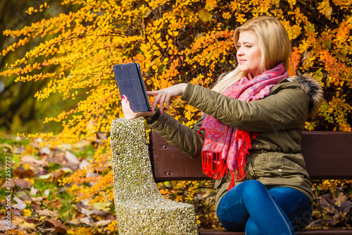 Woman relaxing sitting on bench in park using tablet