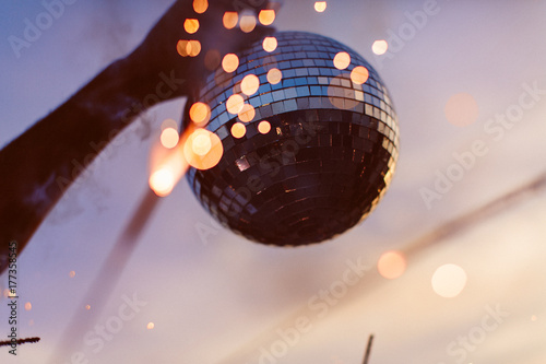 A person holding up a disco ball at the beach photo
