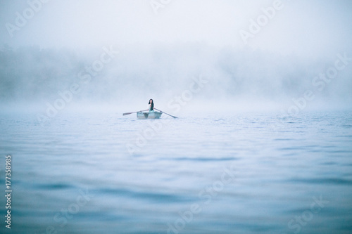 Mystical woman in row boat on a foggy New England morning