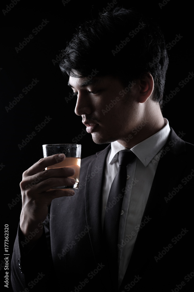 portrait of Asian man in black formal suit with a glass of whisky portrait of Asian man in black formal suit with a glass of whisky
