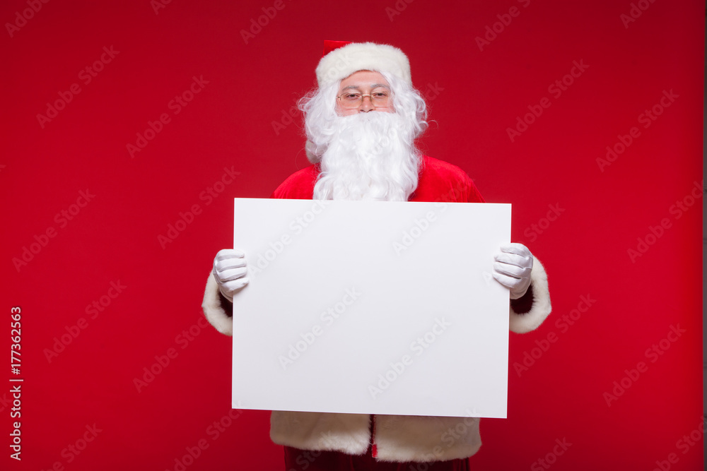 Santa Claus pointing in blank advertisement banner isolated on red background with copy space Santa Claus pointing in blank advertisement banner isolated on red background with copy space