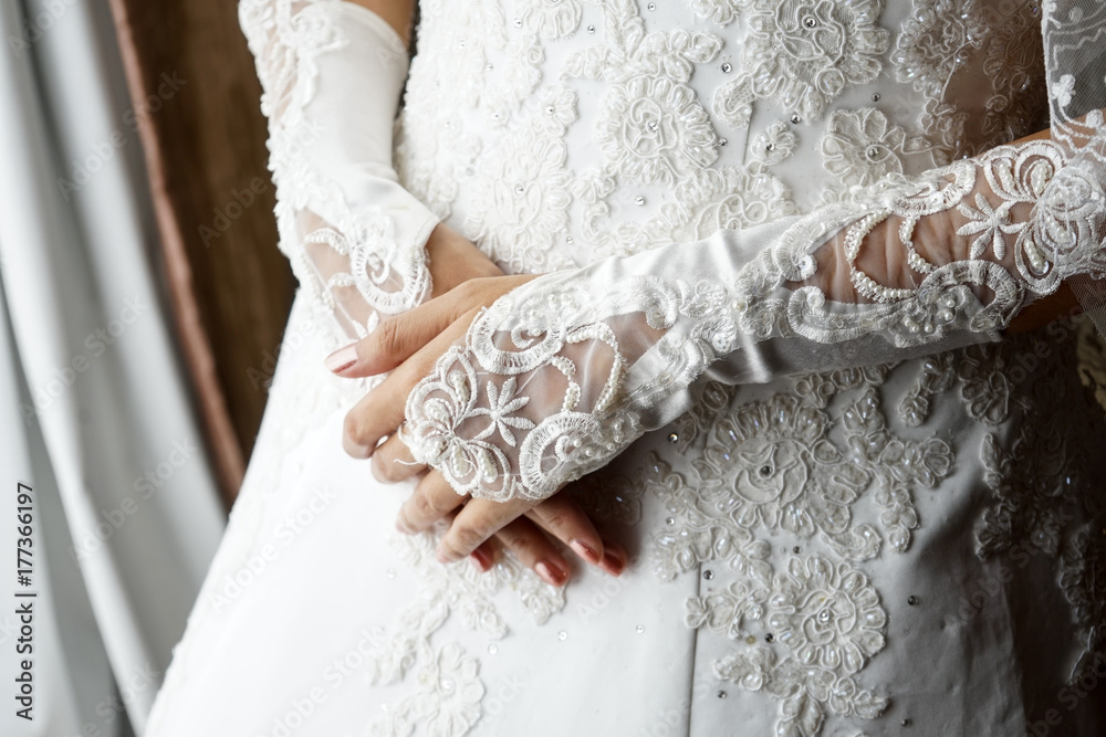 The bride with wedding gloves on a hands on the wedding dress morning preparation for the wedding white nails manicures The bride with wedding gloves on a hands on the wedding dress morning preparation for the wedding white nails manicures