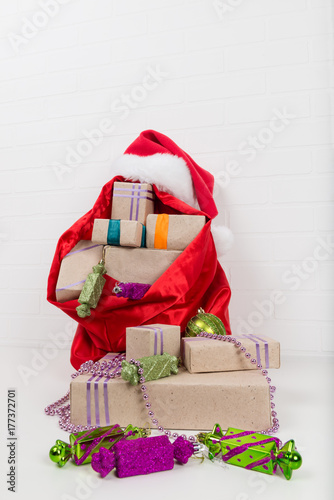 red bag with gifts on the background of a white brick wall