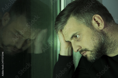 Fototapeta Naklejka Na Ścianę i Meble -  Worried man looking through window