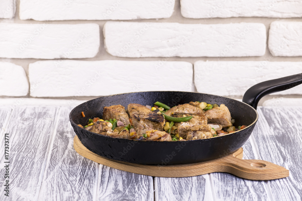 frying pan with fried meat, vegetables 