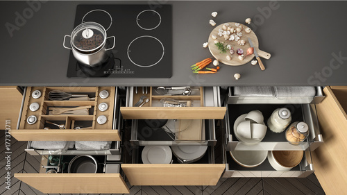 Opened wooden kitchen drawer with accessories inside, solution for kitchen storage and organizing, cooking, modern interior design