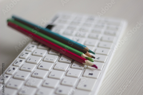 Colored pencils lying on a white computer keyboard, business concept