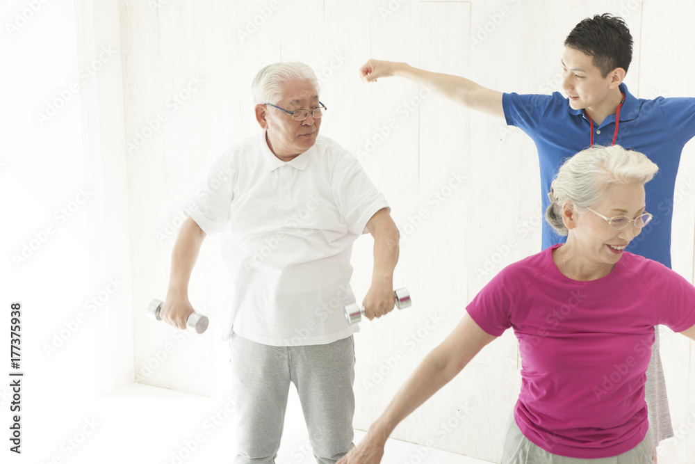 Obraz premium An old couple is doing dumbbell training with a trainer