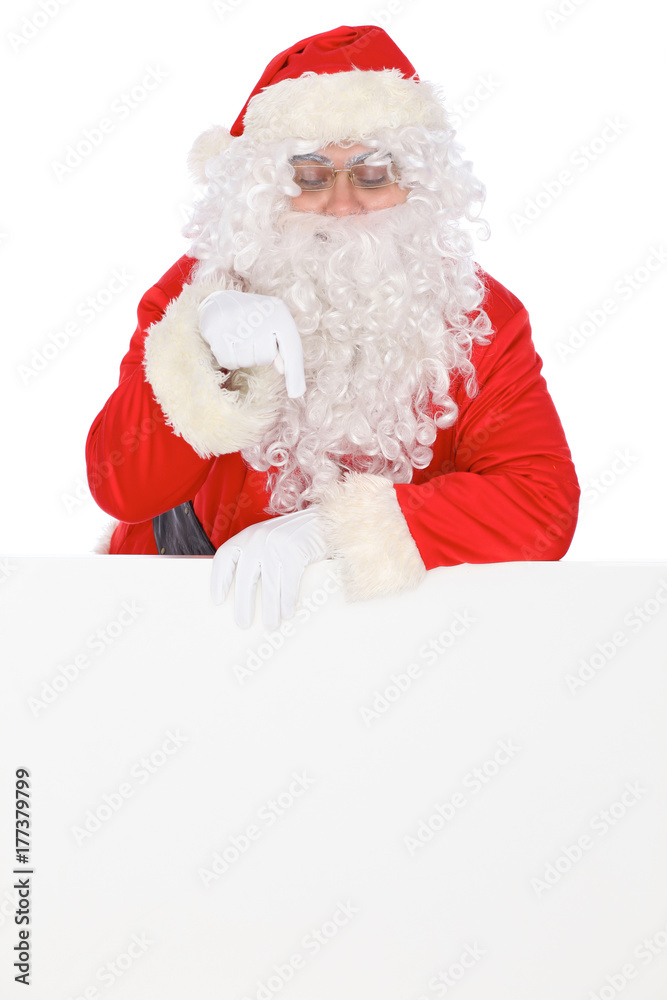 Naklejka premium Santa Claus pointing on blank white wall, advertisement banner with copy space. Isolated on white background