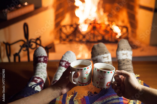 A man and a woman in front of a fireplace in warm socks. New Year. Christmas.