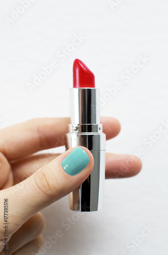 red lipstick in hand with blue manicure
