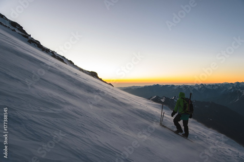 climber at sunrise early morning walks on the slope and on the ground above the snow sweeps drifting snow