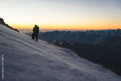 climber at sunrise early morning walks on the slope and on the ground above the snow sweeps drifting snow