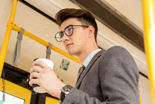 man with coffee to go in public transport