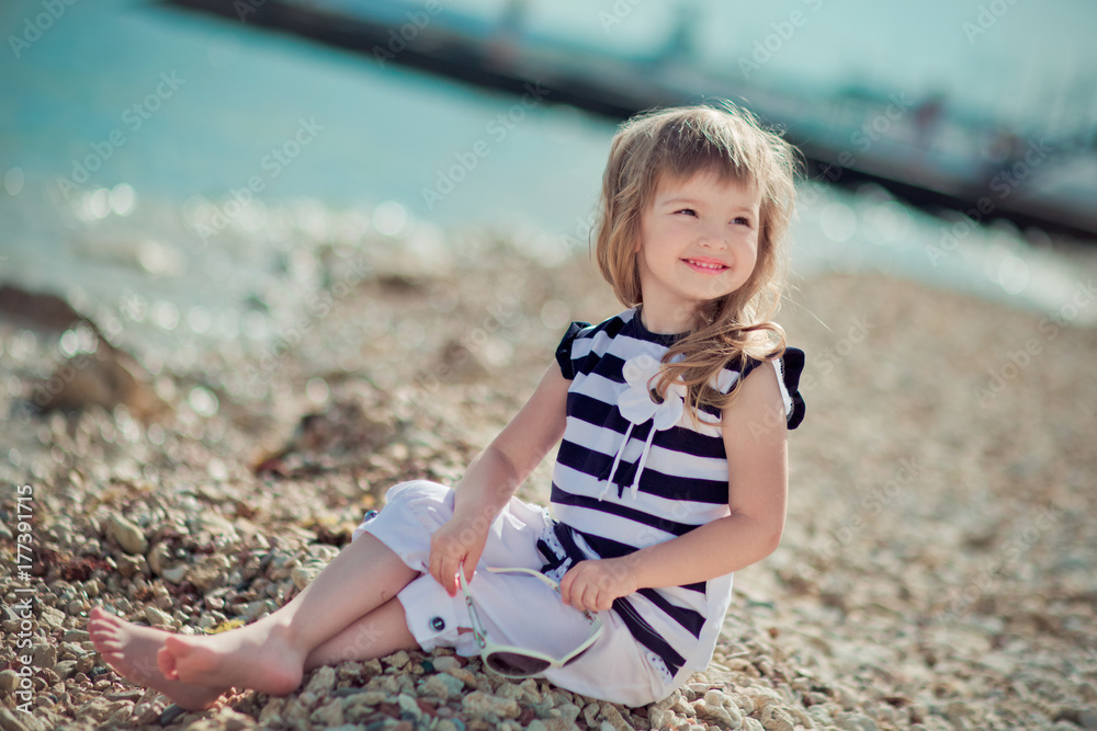Stylish dressed blond child girl enjoy posing summer vacation on public city beach wearing casual bright clothes happy smiling on camera alone Stylish dressed blond child girl enjoy posing summer vacation on public city beach wearing casual bright clothes happy smiling on camera alone