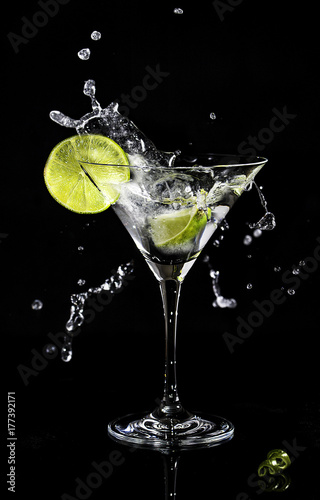 Martini splash in a cocktail glass with a slice of lime on a side