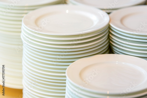 Stacks of cleaned white plates for catering buffet in restaurant room