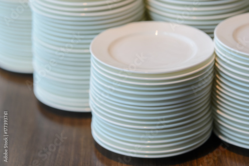 Stacks of cleaned white plates for catering buffet in restaurant room