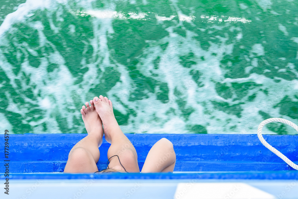 Girl legs hang off edge Passenger boat in ocean.Look at the top.