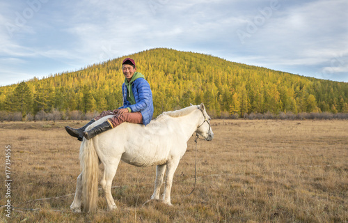 mongolian young man sitting on a white horse photo