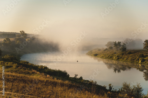 Fisherman on the river in the early foggy morning