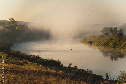 Fisherman on the river in the early foggy morning