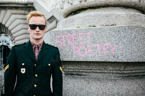 Young blonde man standding next to 'street poetry' chalk graffiti photo