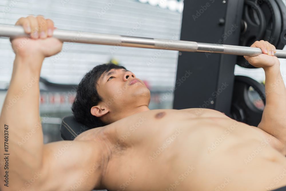 Fitness man in training showing exercises with barbells in gym