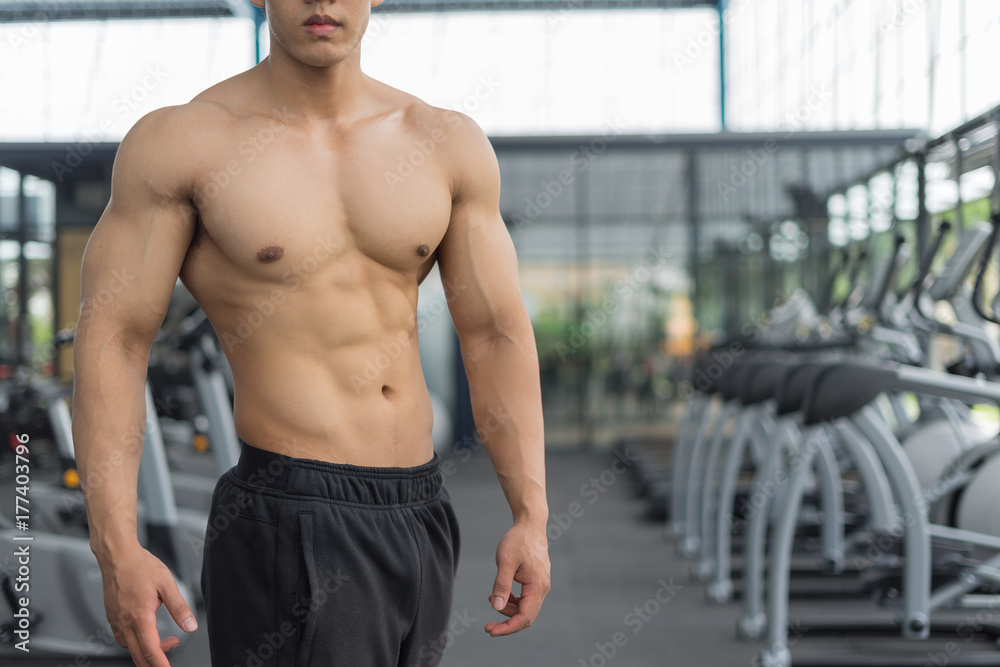 Obraz premium Fitness man showing muscular body in gym